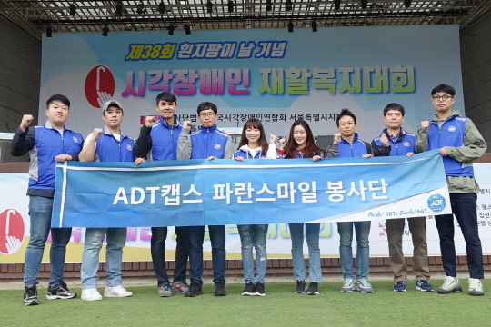 ADT캡스가 지난 12일 서울 능동 어린이대공원에서 열린 '제38회 흰지팡이의 날 기념 시각장애인 재활복지대회'에서 시각장애인들의 원활한 행사 참여를 돕는 봉사활동을 실시했다. 봉사 참여자들이 기념사진을 촬영하고 있다. ADT캡스 제공